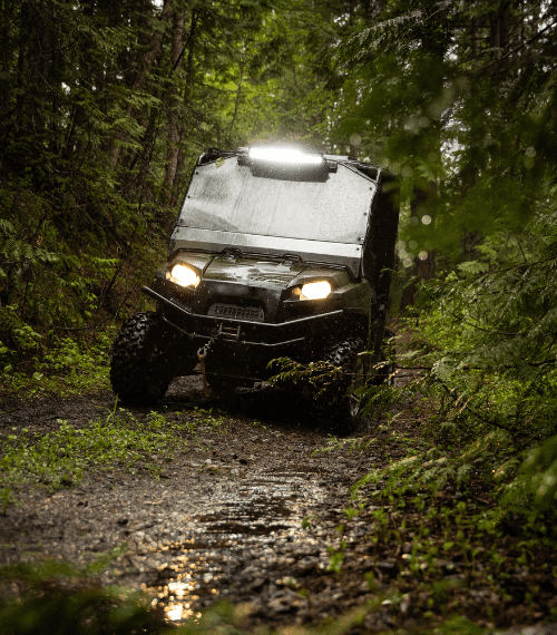 Picture of a UTV in a jungly and muddy environment.