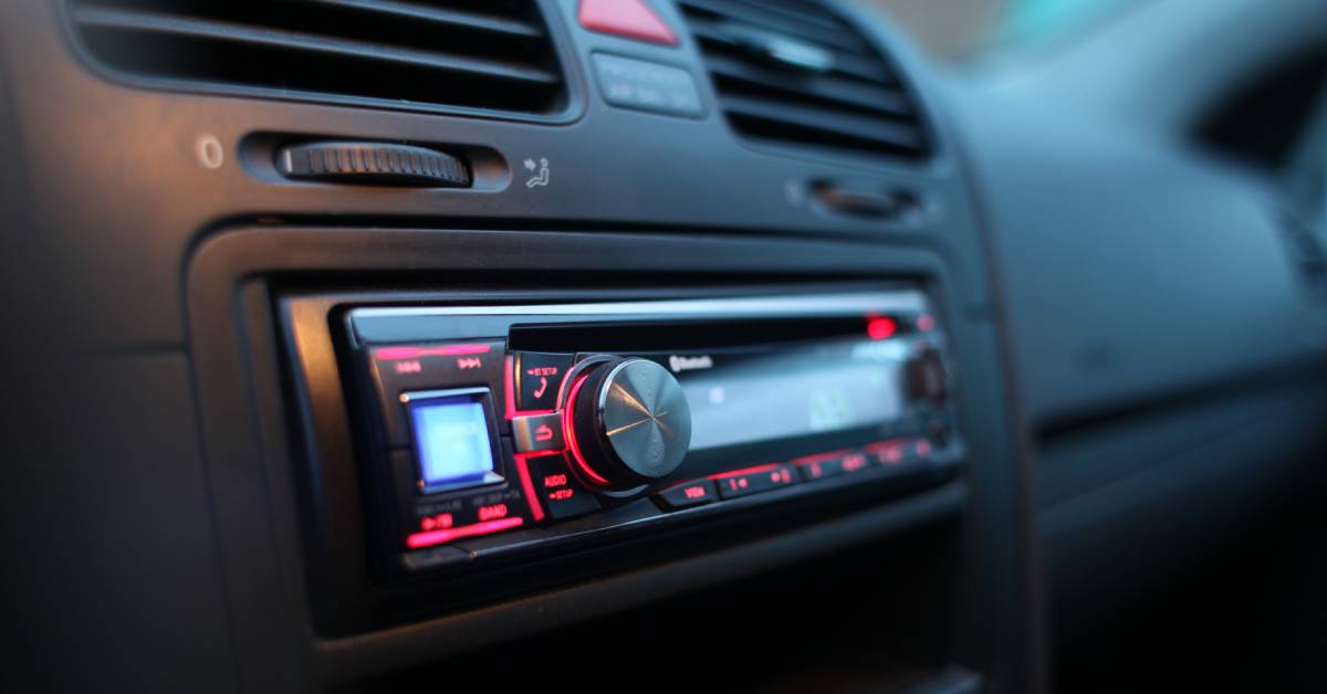 A closeup of a small car stereo. There are only a few buttons and a red backlight that illuminates them. 