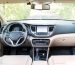 The interior of a vehicle that is mostly while with black accents. The car is on a small road surrounded by trees.